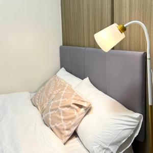 a bed with a lamp and a pillow on it at Condo in Quezon City, Trees Residences Tower 16 in Manila