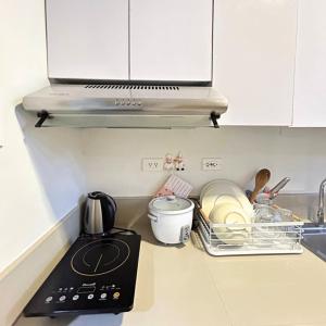 a kitchen counter with a stove and some dishes at Condo in Quezon City, Trees Residences Tower 16 in Manila