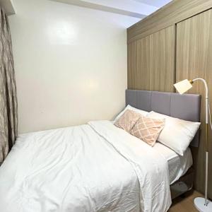 a bedroom with a bed with white sheets and a lamp at Condo in Quezon City, Trees Residences Tower 16 in Manila