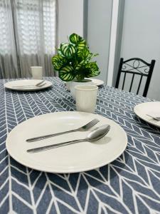 a table with white plates and silverware on it at 3BR MINIMALIST Homestay NEAR KKIA Cyber City in Kapayan