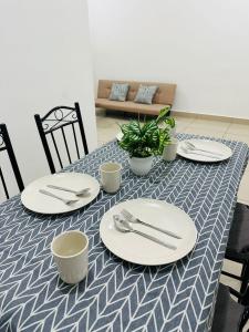 a table with white plates and utensils on it at 3BR MINIMALIST Homestay NEAR KKIA Cyber City in Kapayan