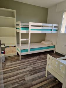 een slaapkamer met 2 stapelbedden en een houten vloer bij Sainte Cécile: appartement 2ch 6/7 pers in Camiers