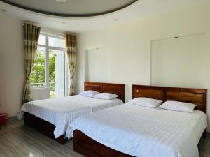 Duas camas num quarto com lençóis brancos em HOTEL 86 PHAN THIẾT em Ấp Bình Hưng