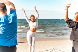 un grupo de personas de pie en la playa con los brazos en alto en Neptuno Resort & Spa, en Dźwirzyno
