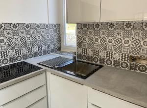 a kitchen with a sink and black and white tiles at MAISON VENEUX LES SABLONS-FONTAINEBLEAU-MORET SUR LOING in Veneux-les-Sablons