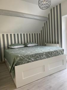 a white bed in a room with a striped wall at MAISON VENEUX LES SABLONS-FONTAINEBLEAU-MORET SUR LOING in Veneux-les-Sablons