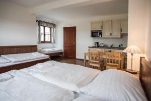 a bedroom with two beds and a kitchen with a table at Apartmány Chajdovka in Boží Dar