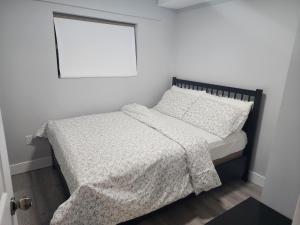 a bedroom with a bed with a blanket and a window at Blissfull Two Bedroom Suite Near surrey centre in Surrey