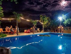 a large blue swimming pool at night with people sitting at Jungle Boss Homestay in Phong Nha