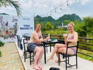 un homme et une femme assis à une table avec des boissons dans l'établissement Jungle Boss Homestay, à Phong Nha
