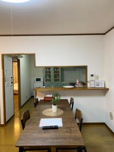 ein Esszimmer mit einem Tisch und einer Küche in der Unterkunft Guest House Flora Otemachi/フローラ大手町 in Hiroshima