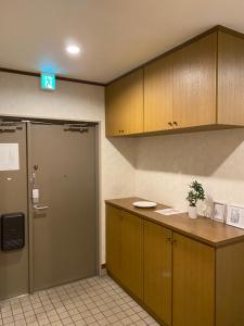 eine Küche mit Holzschränken, einer Tür und einer Theke in der Unterkunft Guest House Flora Otemachi/フローラ大手町 in Hiroshima
