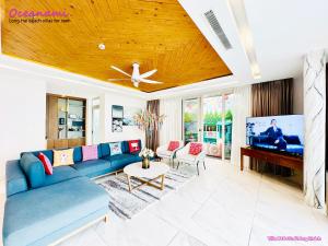 ein Wohnzimmer mit einem blauen Sofa und einem Flachbild-TV in der Unterkunft Villa 1602 Oceanami, Sát biển, Hồ bơi riêng, 837m2 in Long Hải