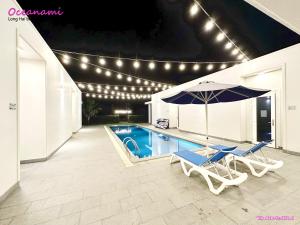 einen Pool mit 2 Stühlen und einem Sonnenschirm in der Unterkunft Villa 1602 Oceanami, Sát biển, Hồ bơi riêng, 837m2 in Long Hải