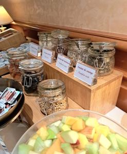 a table with jars of food and a bowl of fruit at Hotel Mirabeau, BW Signature Collection, Lausanne in Lausanne