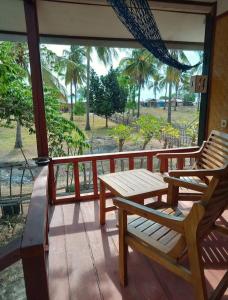 a porch with two wooden chairs and a table at Why Not Bar And Bungalows #2 in Pawenang