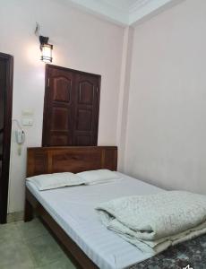 a bedroom with a bed with white sheets and a wooden headboard at Nhà Nghỉ Hương Thúy - TTTM Royal City in Hanoi