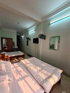 een slaapkamer met 2 bedden, een tv en een spiegel bij Nhà Nghỉ Hương Thúy - TTTM Royal City in Hanoi