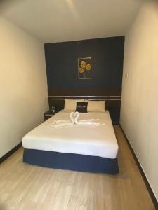 een slaapkamer met een wit bed en een zwarte muur bij Alia Express Sendayan in Kampong Baharu Jimah