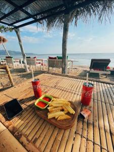 a wooden table with a plate of food and two drinks at Why Not Bar And Bungalows #3 in Pawenang