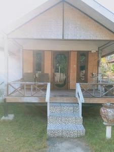 a porch of a house with chairs and tables at Why Not Bar And Bungalows #3 in Pawenang