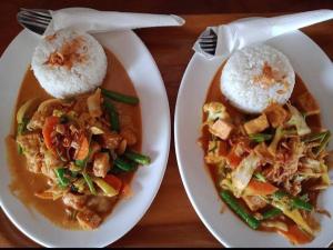 two plates of food with rice and vegetables on a table at Why Not Bar And Bungalows #3 in Pawenang +5 photos