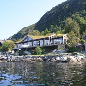 a house on the shore of a body of water at Småstranda Fjord Lodge in Åheim