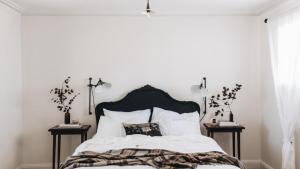 a bedroom with a black and white bed with two side tables at Picketts Cottage in Beechworth