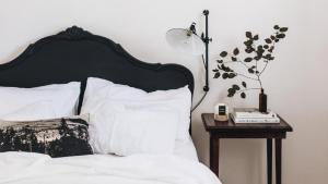 a bed with a black headboard and a table with a lamp at Picketts Cottage in Beechworth