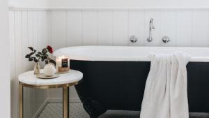 ein Badezimmer mit einer schwarz-weißen Badewanne und einem Tisch in der Unterkunft Picketts Cottage in Beechworth