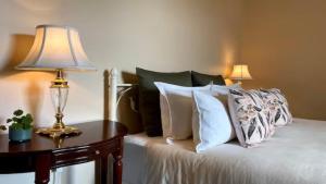 比奇沃斯The Beechworth Conservatory的一张带枕头的床和一张带台灯的桌子