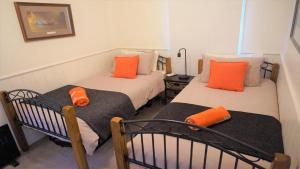two beds in a room with orange pillows on them at Gladstone House in Beechworth