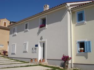 a white house with flowers in the window at Studio Apartment Ivo in Cres