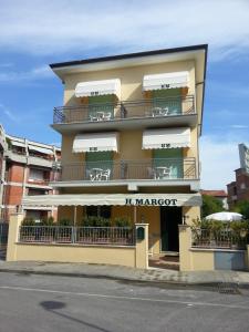 a building with balconies and tables on a street at Hotel Margot in Lido di Camaiore