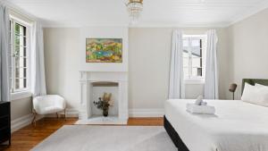 a white bedroom with a bed and a fireplace at 1858 - The Prospect in Beechworth
