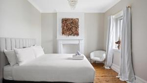 a white bedroom with a white bed and a chair at 1858 - The Prospect in Beechworth