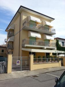 a large yellow building with balconies and a parking lot at Hotel Margot in Lido di Camaiore