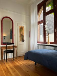 a bedroom with a bed and a desk and a mirror at Altbauwohnung in Gründerzeitvilla in Wuppertal +6 photos