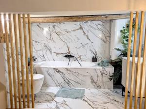a bathroom with a white tub and a marble wall at LOFT Centre Ville 2 Parking in Toulon