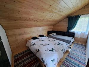 a bedroom with a bed in a wooden cabin at CABANA MERISORULUI in Borşa
