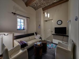 uma sala de estar com um sofá e cadeiras e um relógio em Flat in water mill 10 km from Maastricht em Withuis