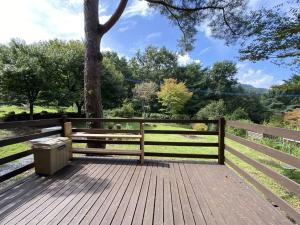 a wooden deck with a bench and a tree at 南阿蘇Villagehouseらかん in Minami Aso