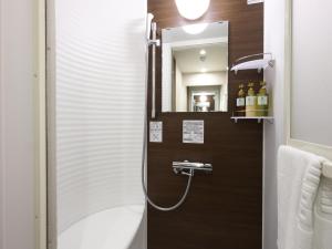 Dormy Inn Hiroshima Annex في هيروشيما: حمام مع دش مع حوض ومرآة