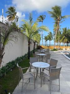 a row of tables and chairs with palm trees at Residencial Taormina - apartamento à beira-mar novinho! in Tamandaré