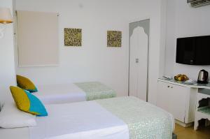 two beds in a white room with a tv at Dahab Lagoon Club & Resort Ex Tirana Dahab in Dahab