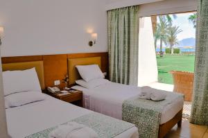 a hotel room with two beds and a large window at Dahab Lagoon Club & Resort Ex Tirana Dahab in Dahab