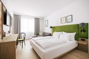 een slaapkamer met een groot wit bed en een groen hoofdeinde bij Bio-Hotel Schani Wienblick in Wenen