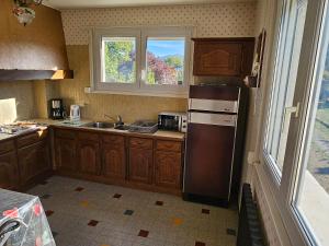 a kitchen with a refrigerator and a sink and a window at La Bourzede F3 in Langeac