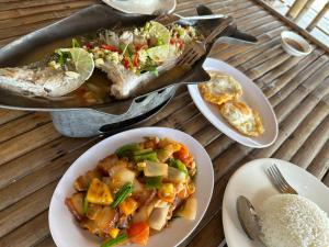 una tavola con piatti di cibo e una padella di pesce di Thmorda Riverview Resort a Koh Kong