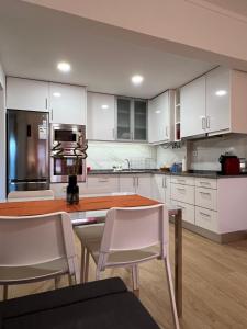 cocina con armarios blancos, mesa y sillas en Vasco da Gama GuestHause-60m2 en Lisboa